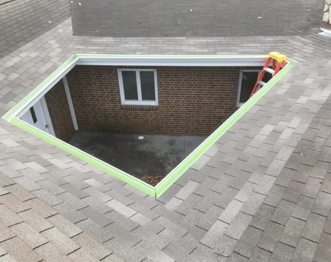 Roof with a large rectangular hole showing a brick wall with windows and a door, and a ladder.